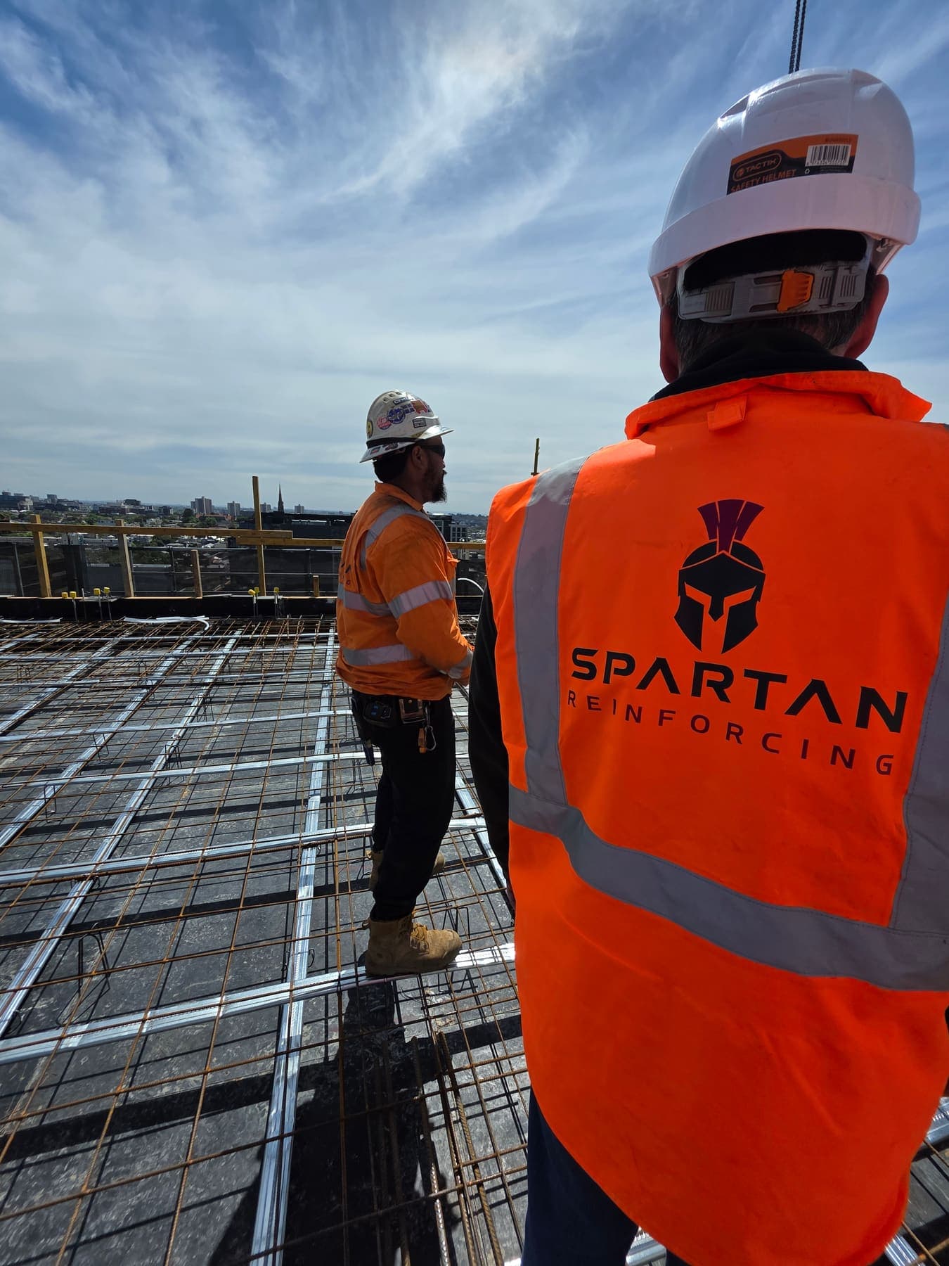 A steel fixer in a Spartan Reinforcing vest on a deck overlooking the Melbourne skyline